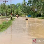 Pengendara sepeda motor melintasi jalan terendam banjir di Desa Rayeuk Kareung, Kecamatan Blang Mangat, Kota Lhokseumawe, Rabu (21/12/2022). (ANTARA/Dedy Syahputra)