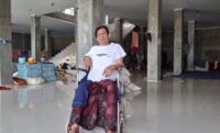 Mukhtar dan kursi roda kala banjir bandang melanda di Pidie Jaya POPULARITAS.COM - Pidie Jaya, satu dari 18 kabupaten dan kota di Aceh yang terdampak langsung bencana banjir bandang dan tanah longsor. Saat air bah menghumbalang kabupaten itu, Mukhtar (45), saksi hidup yang melihat secara nyata kala luapan gemuruh air, lumpur dan gelondongan kayu menyapu habis apapun. Selasa 25 November 2025 malam hari, kata Mukhtar mengawali kisahnya. Dari atas kursi rodanya, Ia melihat air mulai meluap dan masuk ke rumah-rumah warga. Saat itu, ia tengah berbaring diatas kasur di rumahnya. Mukhtar tinggal di Gampong Meunasah Lhok, Meureudu, Pidie Jaya. Dirinya yang tak bisa bergerak sebab lumpuh, saat itu menyaksikan detik demi detik air mulai memenuhi kamar tidurnya. Selang beberapa saat kemudian, ketinggian air telah menenggelamkan tempatnya berbaring. Ya, situasi itu tak membuatnya pasrah. Ia mengaku, meski kondisi tubuhnya terbatas akibat kelumpuhan, dirinya tak menyerah. “Saya lumpuh akibat kecelakaan motor 13 tahun lalu,” kata Mukhtar mengawali kisahnya kepada popularitas.com, Selasa 6 Januari 2026. Saat berbincang dengan popularitas.com, Mukhtar duduk dengan santai diatas kursi rodanya. Lelaki itu mengenakan kaos putih. Sorot matanya tajam dan bicaranya tenang dan kalimat yang disampaikannya mengalir. Sembari membenarkan posisi duduknya, Mukhtar melanjutkan ceritanya. Saat itu, banjir sudah masuk ke rumah. Meski kondisi tubuhnya yang terbatas, namun dirinya tetap berupaya ingin selamat. Saat itu, air makin deras dan terus meninggi. Dalam situasi yang pelik, adiknya Muksalmina (35) pun datang melihatnya. Dengan sigap, keduanya pun berhasil menyelamatkan diri dengan dua lembar papan. “Tubuh saya dibaringkan diatas papan oleh adik saya. Lalu kami berenang menyelamatkan diri,” imbuhnya. Saat itu, sambungnya lagi, ketinggian air telah mencapai 1,5 meter. Namun, ia bersama adik dan kakaknya terus berenang menyelamatkan diri. Sementara, seluruh perkampungan telah rata dengan genangan air. “Kira-kira saat kami berenang itu, ketinggian banjir sudah capai 1,5 meter,” ucapnya. Malam terus bergerak, bahkan hingga jelang subuh. Lantunan ayat alquran yang biasa nyaring dari pengeras suara masjid, waktu itu tidak terdengar. Yang ada hanya gemuruh air dan suara orang-orang yang saling menyelamatkan diri. Ia mencoba melirik jam tangannya yang berembun. Samar-samar, jarum jam menujuk pukul 04.20 WIB. Namun, luapan air tak berhenti dan justru kian tinggi. “Saat itu, yang ada dalam pikiran hanya menyelamatkan diri dan minta bantuan,” ujarnya lagi. Sebagai korban banjir, Mukhtar kini tinggal di Posko Pengungsian Gampong Meunasah Lhok. Bangunan toko milik yang belum rampung milik Haji Wan itu, kini dijadikan tempat penampungan sementara oleh warga. Dalam situasi kegentingan, ia pun mencoba menghubungi para pihak, saudara-saudara, para pejabat dan nomor siapa saja yang tersimpan dalam memori hapenya, sambung Mukhtar melanjutkan kisahnya. Meski hapenya tak ada pulsa, Mukhtar berharap ada keajaiban yang bisa membuatnya terhubung dengan orang-orang yang bisa memberikan bantuan dan pertolongan. “Saya sadar ponsel tak ada pulsa, tapi berharap ada keajaiban,” sebutnya. Tak terbilang beberapa kali ia mencoba peruntungan lewat hape yang digengamnya itu. Nyaris tidak ada terhubung. Bahkan, kenalannya di badan penanggulangan bencana pun tak luput ia telpon. “Saat itu, jika ada keajaiban bisa terhubung, rasanya hanya ingin minta dikirimkan perahu karet atau evakuasi,” ungkapnya. Butuh Kursi Roda Mukhtar mengaku, meski tinggal di pengungsian, dirinya tetap bersyukur. Sebab, Allah SWT masih memberinya kesempatan hidup dan beramal. Kini, pascabencana, harapan yang ia miliki hanya kursi roda baru. “Saya butuh kursi roda, yang ini sudah rusak,” katanya. Karna itu, dirinya berharap ada pihak-pihak yang bisa membantunya mendapatkan kursi roda, untuk menopang kehidupannya yang serba dalam keterbatasan. Ia pun berharap, daerah-daerah yang dilanda banjir bandang bisa cepat pulih, terutama kampung tempatnya bermukim. Saat berbincang dengan Mukhtar, beberapa anak-anak berlari dan bersepeda. Pria-pria dewasa sibuk mengangkut bahan-bahan makanan. Bangunan yang dijadikan Posko Pengungsian itu, tak begitu ramai siang itu. Hanya terlihat lalang beberapa kenderaandan hilir mudik orang-orang, serta burung-burung terbang rendah di lokasi pengungsian tersebut. Mukhtar tentu ingin cepat pulang, pun begitu ratusan warga lainnya yang tinggal sementara di bangunan dua lantai itu. Harapan lelaki berkursi roda itu, sama seperti keinginan masyarakat lainnya, bisa segera pulang dan menata kehidupan dan masa depan kembali.