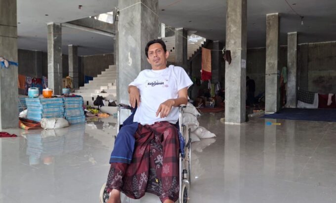 Mukhtar dan kursi roda kala banjir bandang melanda di Pidie Jaya POPULARITAS.COM - Pidie Jaya, satu dari 18 kabupaten dan kota di Aceh yang terdampak langsung bencana banjir bandang dan tanah longsor. Saat air bah menghumbalang kabupaten itu, Mukhtar (45), saksi hidup yang melihat secara nyata kala luapan gemuruh air, lumpur dan gelondongan kayu menyapu habis apapun. Selasa 25 November 2025 malam hari, kata Mukhtar mengawali kisahnya. Dari atas kursi rodanya, Ia melihat air mulai meluap dan masuk ke rumah-rumah warga. Saat itu, ia tengah berbaring diatas kasur di rumahnya. Mukhtar tinggal di Gampong Meunasah Lhok, Meureudu, Pidie Jaya. Dirinya yang tak bisa bergerak sebab lumpuh, saat itu menyaksikan detik demi detik air mulai memenuhi kamar tidurnya. Selang beberapa saat kemudian, ketinggian air telah menenggelamkan tempatnya berbaring. Ya, situasi itu tak membuatnya pasrah. Ia mengaku, meski kondisi tubuhnya terbatas akibat kelumpuhan, dirinya tak menyerah. “Saya lumpuh akibat kecelakaan motor 13 tahun lalu,” kata Mukhtar mengawali kisahnya kepada popularitas.com, Selasa 6 Januari 2026. Saat berbincang dengan popularitas.com, Mukhtar duduk dengan santai diatas kursi rodanya. Lelaki itu mengenakan kaos putih. Sorot matanya tajam dan bicaranya tenang dan kalimat yang disampaikannya mengalir. Sembari membenarkan posisi duduknya, Mukhtar melanjutkan ceritanya. Saat itu, banjir sudah masuk ke rumah. Meski kondisi tubuhnya yang terbatas, namun dirinya tetap berupaya ingin selamat. Saat itu, air makin deras dan terus meninggi. Dalam situasi yang pelik, adiknya Muksalmina (35) pun datang melihatnya. Dengan sigap, keduanya pun berhasil menyelamatkan diri dengan dua lembar papan. “Tubuh saya dibaringkan diatas papan oleh adik saya. Lalu kami berenang menyelamatkan diri,” imbuhnya. Saat itu, sambungnya lagi, ketinggian air telah mencapai 1,5 meter. Namun, ia bersama adik dan kakaknya terus berenang menyelamatkan diri. Sementara, seluruh perkampungan telah rata dengan genangan air. “Kira-kira saat kami berenang itu, ketinggian banjir sudah capai 1,5 meter,” ucapnya. Malam terus bergerak, bahkan hingga jelang subuh. Lantunan ayat alquran yang biasa nyaring dari pengeras suara masjid, waktu itu tidak terdengar. Yang ada hanya gemuruh air dan suara orang-orang yang saling menyelamatkan diri. Ia mencoba melirik jam tangannya yang berembun. Samar-samar, jarum jam menujuk pukul 04.20 WIB. Namun, luapan air tak berhenti dan justru kian tinggi. “Saat itu, yang ada dalam pikiran hanya menyelamatkan diri dan minta bantuan,” ujarnya lagi. Sebagai korban banjir, Mukhtar kini tinggal di Posko Pengungsian Gampong Meunasah Lhok. Bangunan toko milik yang belum rampung milik Haji Wan itu, kini dijadikan tempat penampungan sementara oleh warga. Dalam situasi kegentingan, ia pun mencoba menghubungi para pihak, saudara-saudara, para pejabat dan nomor siapa saja yang tersimpan dalam memori hapenya, sambung Mukhtar melanjutkan kisahnya. Meski hapenya tak ada pulsa, Mukhtar berharap ada keajaiban yang bisa membuatnya terhubung dengan orang-orang yang bisa memberikan bantuan dan pertolongan. “Saya sadar ponsel tak ada pulsa, tapi berharap ada keajaiban,” sebutnya. Tak terbilang beberapa kali ia mencoba peruntungan lewat hape yang digengamnya itu. Nyaris tidak ada terhubung. Bahkan, kenalannya di badan penanggulangan bencana pun tak luput ia telpon. “Saat itu, jika ada keajaiban bisa terhubung, rasanya hanya ingin minta dikirimkan perahu karet atau evakuasi,” ungkapnya. Butuh Kursi Roda Mukhtar mengaku, meski tinggal di pengungsian, dirinya tetap bersyukur. Sebab, Allah SWT masih memberinya kesempatan hidup dan beramal. Kini, pascabencana, harapan yang ia miliki hanya kursi roda baru. “Saya butuh kursi roda, yang ini sudah rusak,” katanya. Karna itu, dirinya berharap ada pihak-pihak yang bisa membantunya mendapatkan kursi roda, untuk menopang kehidupannya yang serba dalam keterbatasan. Ia pun berharap, daerah-daerah yang dilanda banjir bandang bisa cepat pulih, terutama kampung tempatnya bermukim. Saat berbincang dengan Mukhtar, beberapa anak-anak berlari dan bersepeda. Pria-pria dewasa sibuk mengangkut bahan-bahan makanan. Bangunan yang dijadikan Posko Pengungsian itu, tak begitu ramai siang itu. Hanya terlihat lalang beberapa kenderaandan hilir mudik orang-orang, serta burung-burung terbang rendah di lokasi pengungsian tersebut. Mukhtar tentu ingin cepat pulang, pun begitu ratusan warga lainnya yang tinggal sementara di bangunan dua lantai itu. Harapan lelaki berkursi roda itu, sama seperti keinginan masyarakat lainnya, bisa segera pulang dan menata kehidupan dan masa depan kembali.